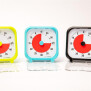 Abbildung 1: Time Timer® Pocket in Gelb, Türkis und Schwarz nebeneinander, frontal mit geöffnetem Deckel