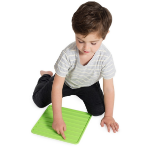 ein Junge der mit dem Finger über eine grüne quadratförmige Strukturmatte fährt