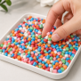 Bunte Thermostar® Sensory Beads Stone aus Silikon in einer weißen Schale auf hellem Untergrund