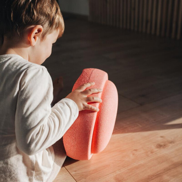 Kind spielt mit zwei Stapelsteinen in Light Red – fördert Bewegung und Fantasie.
